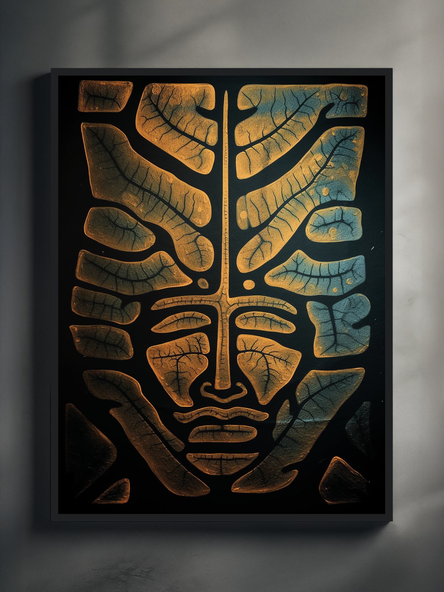 A modern abstract poster showing a symmetrical human face formed from golden-yellow and blue leaves with visible veins. The artwork is framed in black and displayed against a light wall, creating a striking contrast that highlights the organic patterns and facial structure.