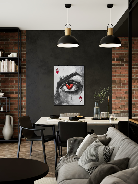 An abstract eye illustration featuring a red heart pupil displayed as wall art on a dark accent wall in a modern industrial living room with brick details, minimalist furniture, and pendant lighting.