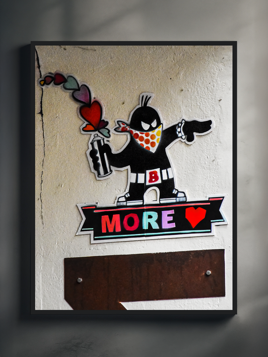 Urban street art style print showing a masked cartoon graffiti character holding a spray can, with colorful heart smoke and the word MORE LOVE on a wall background.