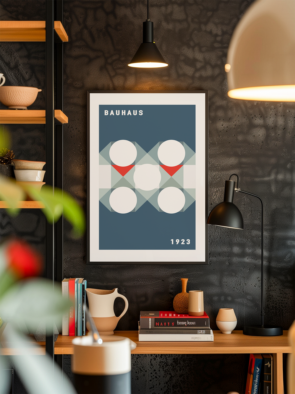 A framed poster reading “Bauhaus 1923” hangs on a dark textured wall above a wooden shelf. The poster features geometric shapes in blue, white, and red. The scene includes modern pendant lighting, books, ceramic vases, and decorative objects, creating a warm, contemporary, and minimalist look with carefully coordinated Bauhaus-inspired design elements.