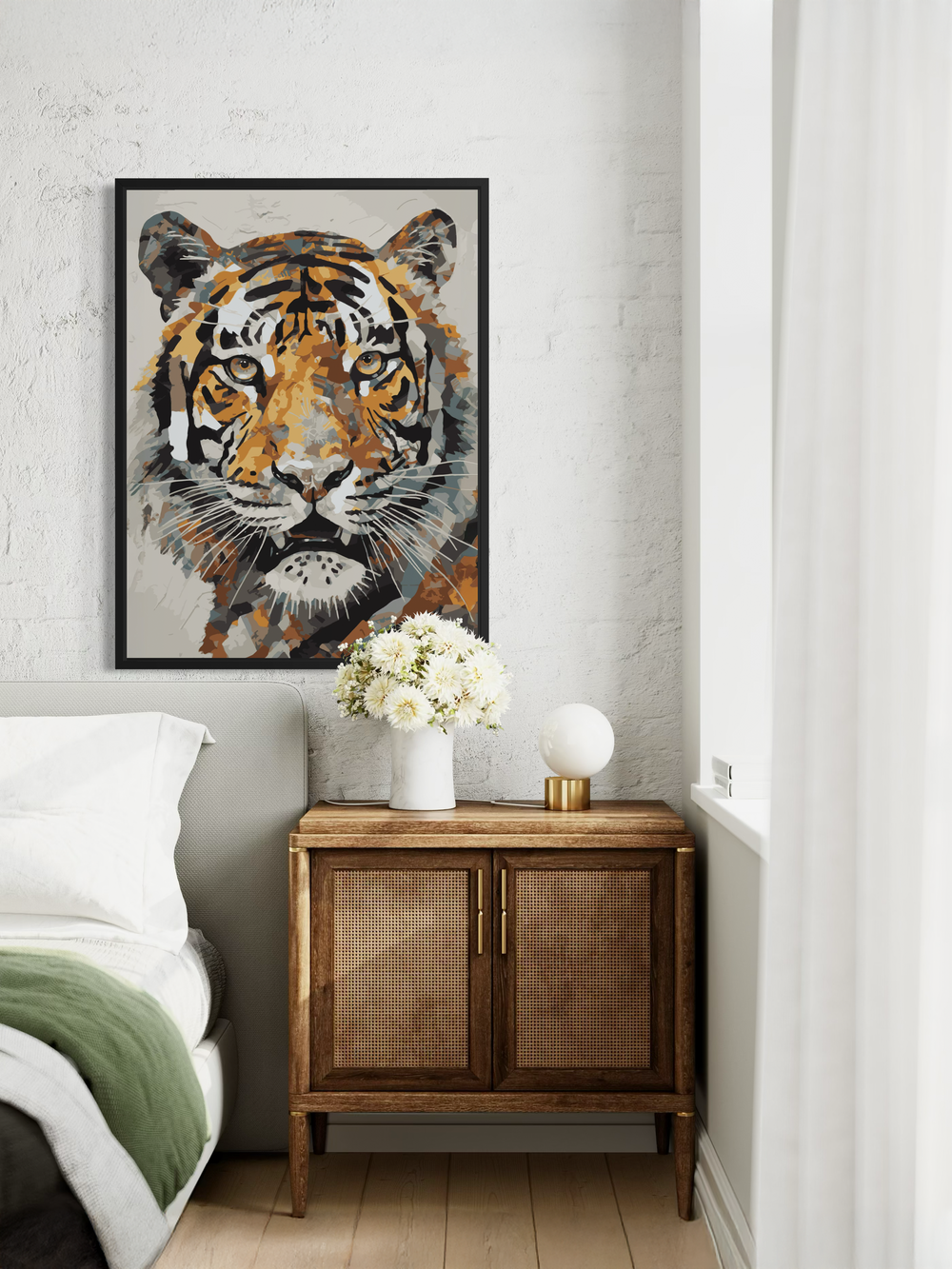 A striking tiger portrait print hangs on a textured light wall above a small cabinet in a calm, modern bedroom. The artwork features an expressive, geometric-style tiger face with warm orange, brown, and grey tones. Soft bedding, neutral colors, and simple decor elements like flowers and a round lamp create a clean and peaceful atmosphere around the bold artwork.