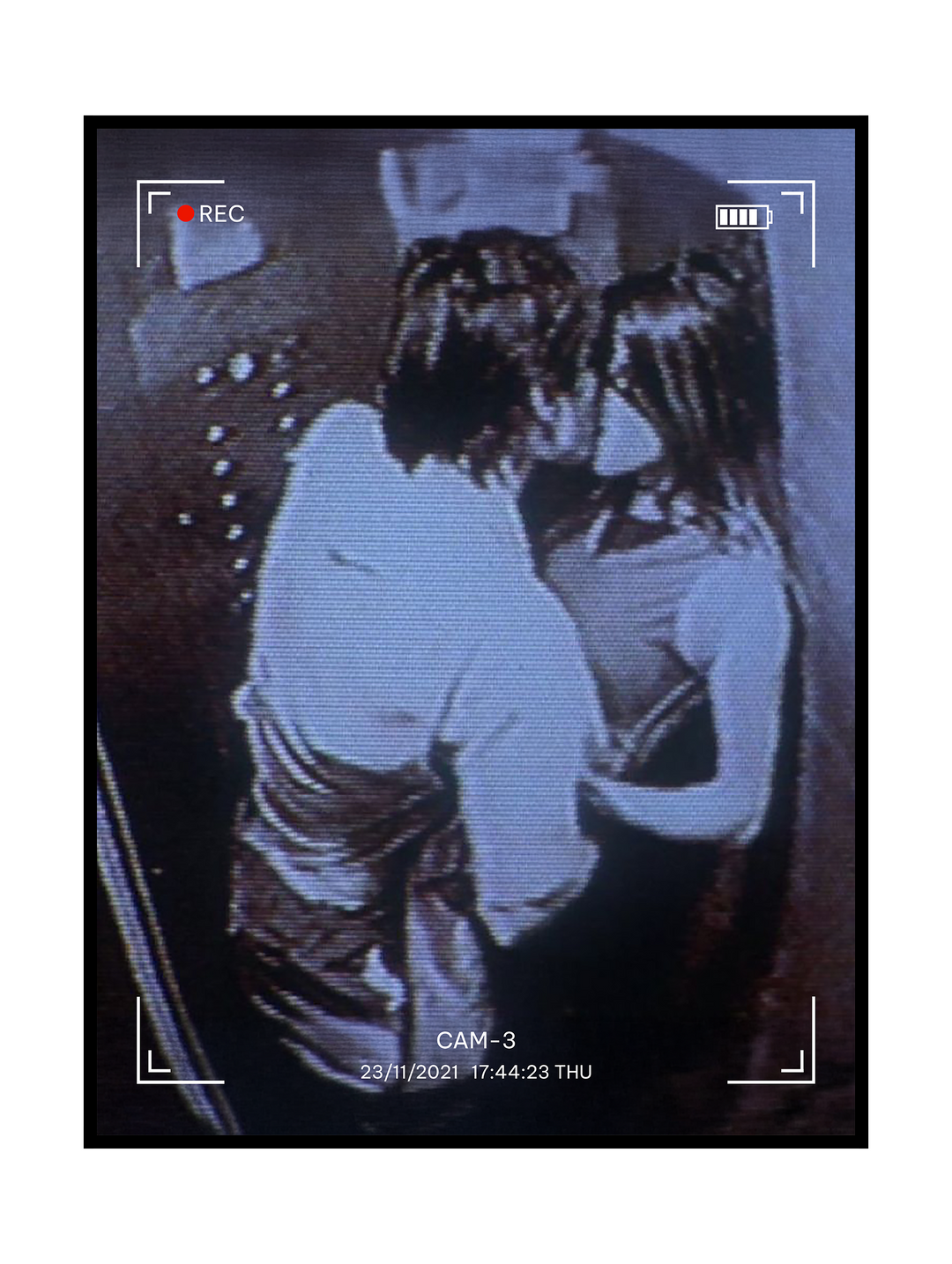 Grainy monochrome artwork depicting a couple embracing, styled like a CCTV surveillance recording with REC indicator, timestamp, and camera frame overlay. The image evokes intimacy, anonymity, and voyeurism through a retro analog video aesthetic, blending emotional closeness with themes of observation and urban realism.