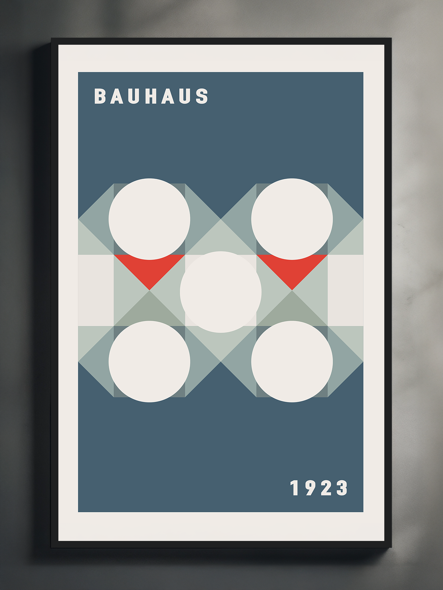 A framed Bauhaus-style artwork displayed against a dark wall, featuring a grid of white circles with intersecting translucent triangles and red accents. The design is minimal and structured, with the word “Bauhaus” at the top left and the year “1923” at the bottom right, set on a deep blue background.