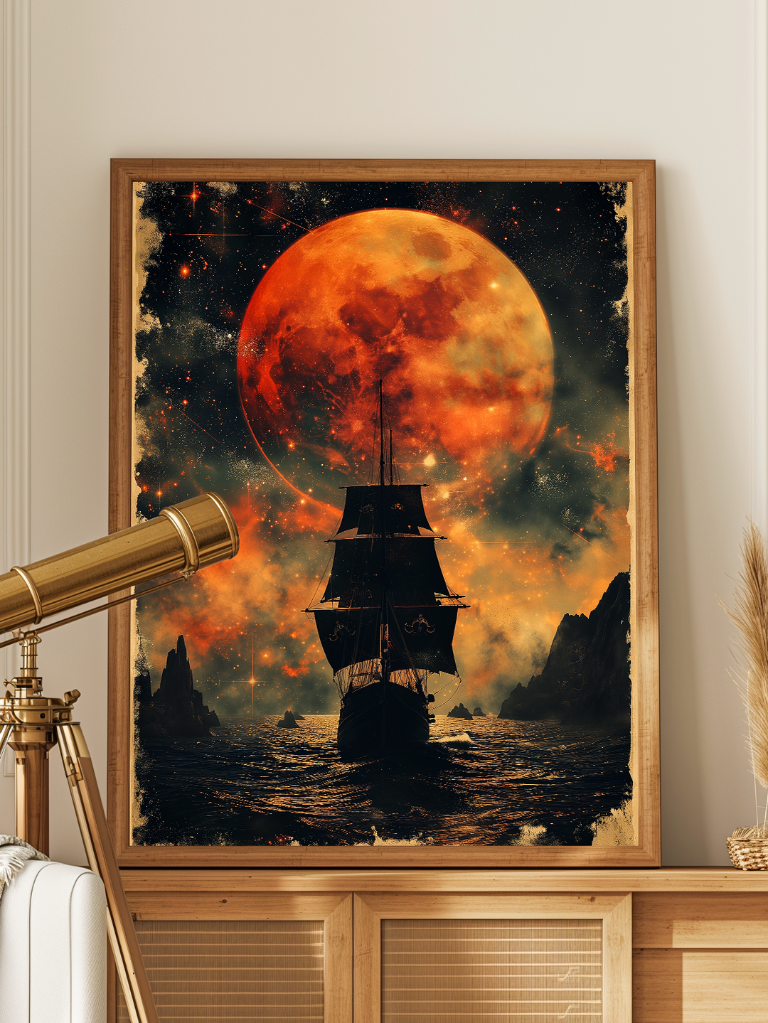 Fantasy poster of a dark pirate ship sailing under a glowing red-orange moon, framed and displayed in a bright modern living space with light wood furniture, white walls, and a brass telescope beside it. The scene blends nautical mystery with contemporary interior design, creating a striking visual contrast.