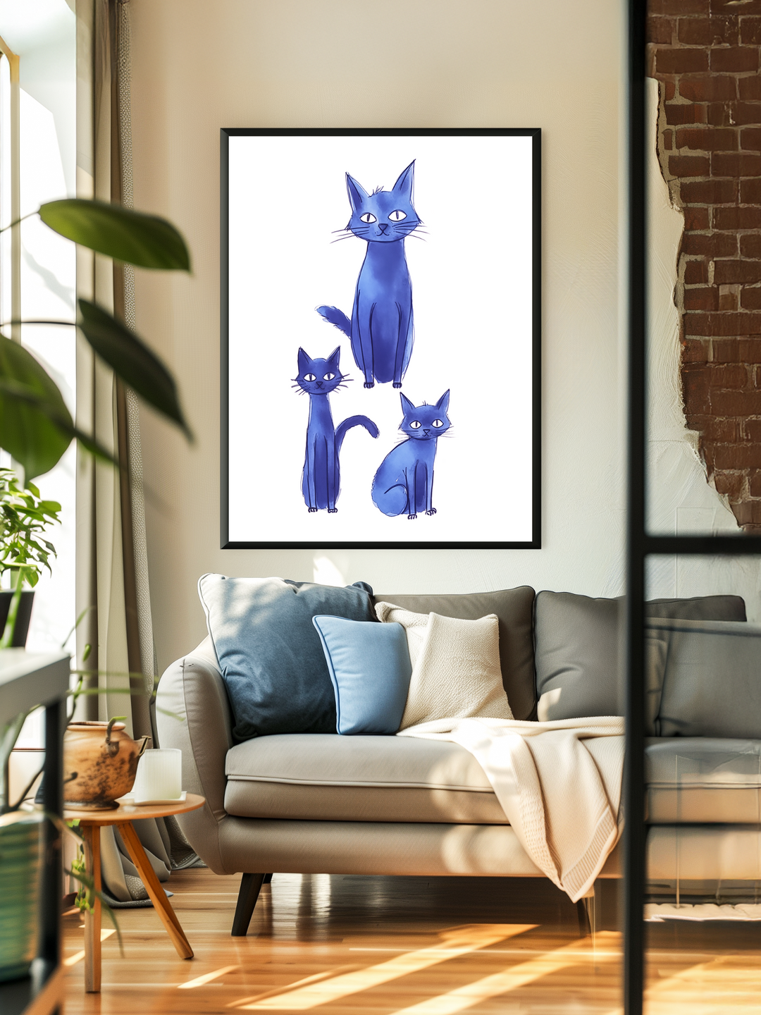 A cozy, sunlit living room featuring a beige sofa with blue and cream cushions, a blanket draped over the armrest, and a large framed poster of three stylized blue cats hanging on the wall. The scene includes soft shadows, indoor plants, and a glimpse of a brick accent wall, creating a warm and inviting atmosphere.