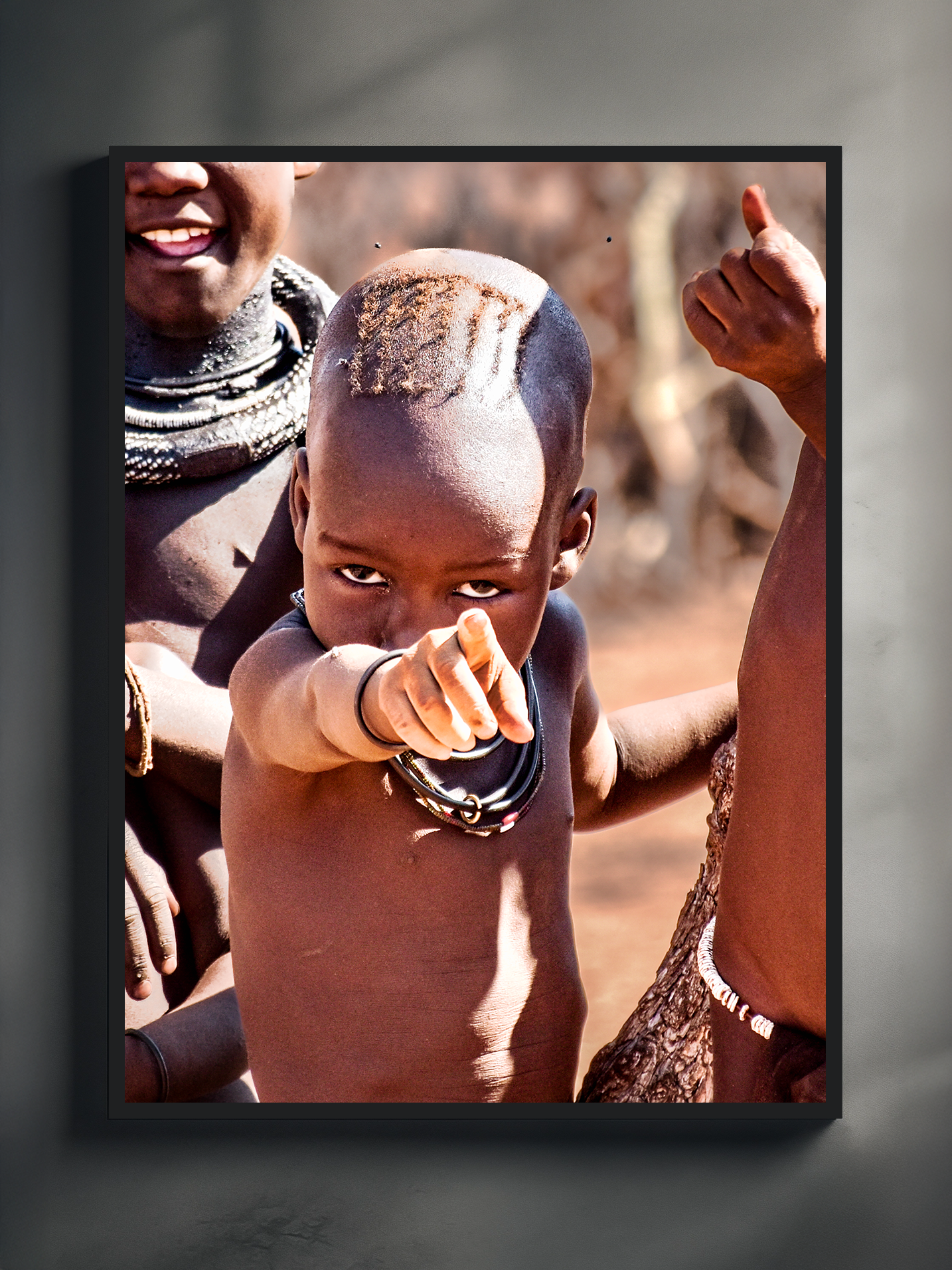 Documentary style photo poster showing a himba child pointing directly at the viewer with an intense gaze, captured in warm natural light.