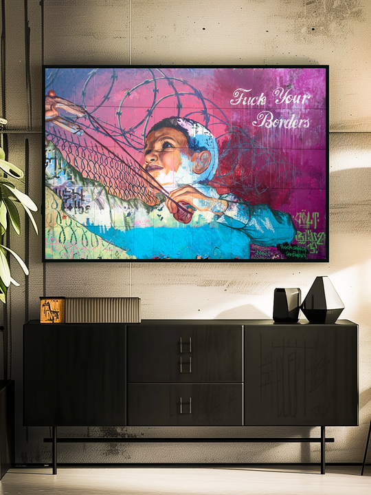 Close-up of a colorful political art print with the words “Fuck Your Borders” displayed in a sleek black frame above a modern sideboard, set in a stylish urban living space with concrete walls and minimalist decor.