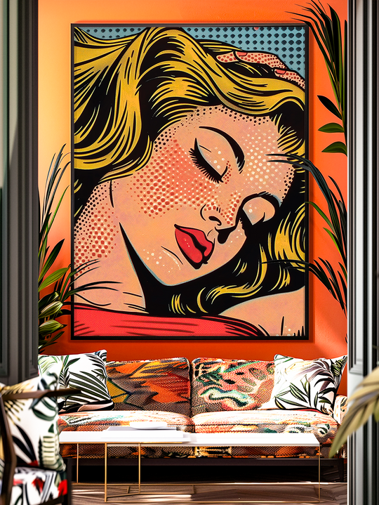 A vibrant pop art wall print of a blonde woman with closed eyes, red lips, and bold comic-style shading, inspired by retro Roy Lichtenstein aesthetics. The artwork features striking colors of yellow, red, black, and blue dots, framed in a modern living space with patterned cushions, tropical plants, and a stylish sofa, creating a bold and artistic atmosphere.