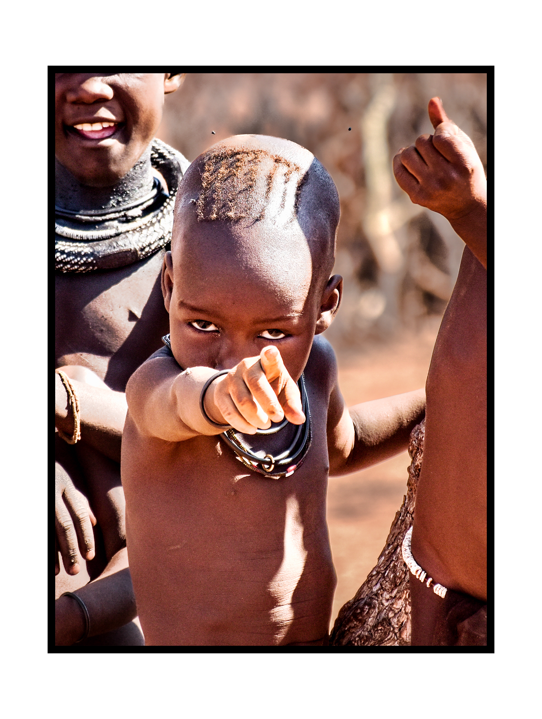 Expressive documentary-style art print capturing a young child with an intense gaze pointing directly toward the viewer. The image conveys strength, curiosity, and human connection, with natural light, earthy tones, and a raw, authentic atmosphere inspired by cultural portrait photography.