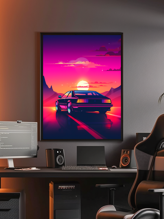 A framed poster featuring a retro sports car and a glowing neon sunset hangs above a sleek black desk setup. The workstation includes a monitor, speakers, a keyboard, and a high-back gaming chair, blending creative studio functionality with a vibrant synthwave-inspired aesthetic.