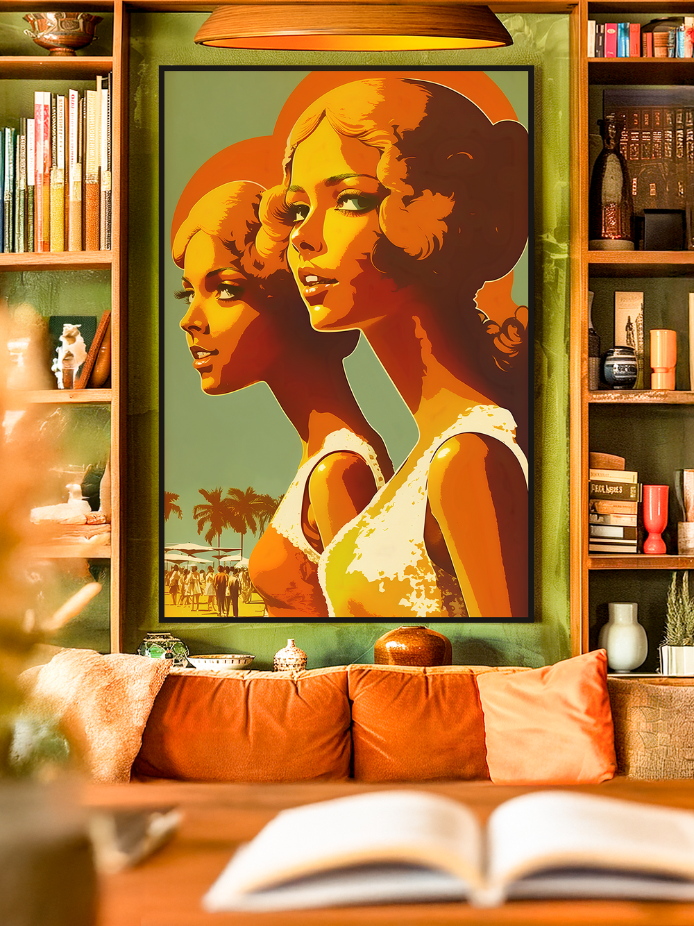 A framed retro-style wall art print featuring two women in warm orange, yellow, and red tones with palm trees in the background. The artwork hangs in a cozy living room with green shelves, books, decorative objects, and warm lighting, creating a bold vintage-inspired atmosphere.