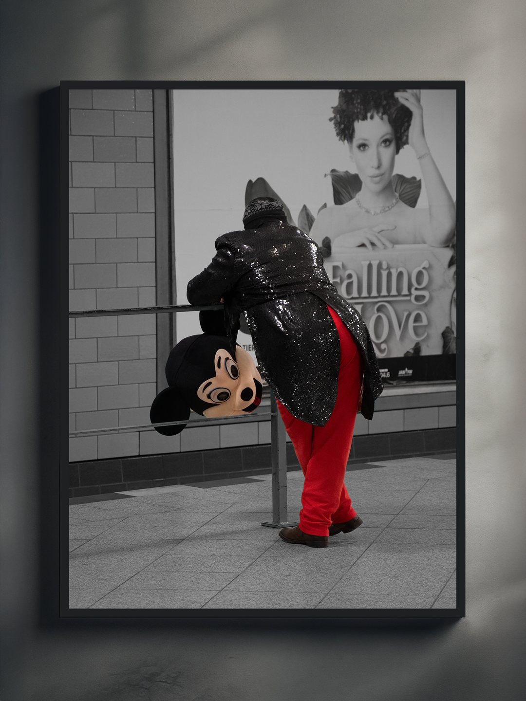 A striking urban-themed art print showing a person in a glittering black sequin jacket and red pants leaning over a railing while holding a Mickey Mouse head. The background features a black-and-white billboard with the words “Falling in Love” and a woman’s portrait, creating a strong visual contrast between color and monochrome for a modern, edgy statement piece.