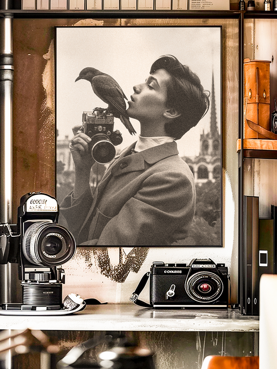 Artistic black and white portrait of a young person in a suit holding a vintage camera while a bird perches on top, creating a surreal and nostalgic mood. The poster is displayed among classic film cameras and retro photography decor, emphasizing a timeless aesthetic that blends fine art and vintage photography.
